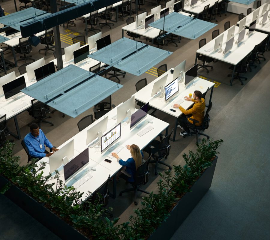 Team of managers works on computers in IT office, top view. Professional teamwork and planning, group brainstorming, modern company interior on background